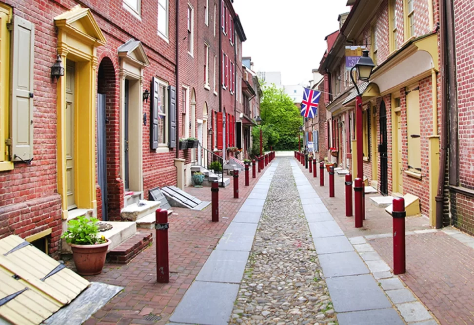 Elfreth’s Alley, narrow cobblestone road lined with red brick and historic 2 story houses.