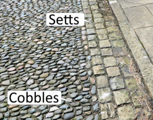 Historic cobblestone road with labeled arrows pointing to cobblestones & setts